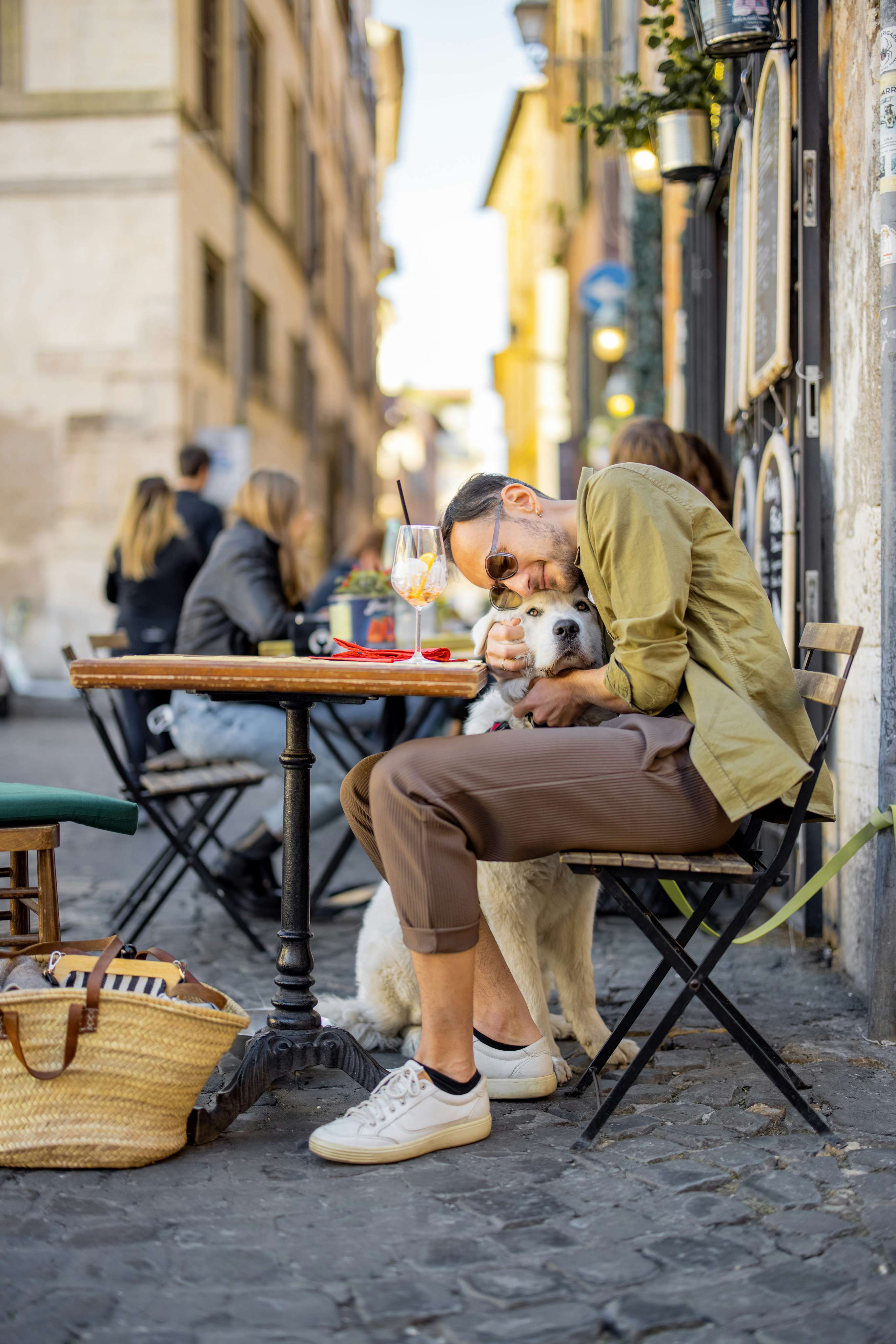 Ospite e cane in un vicolo italiano davanti a un caffè